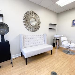 A stylish and modern waiting area in a hair salon, featuring elegant furniture and minimalist decor.