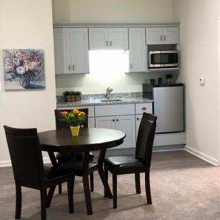 A compact kitchen and dining area with a round table and chairs, featuring modern appliances.