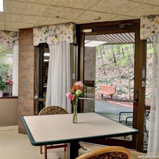 A cozy interior space with a table adorned with flowers and natural light streaming through the window.