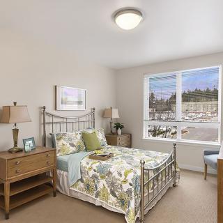 A cozy and well-lit bedroom with a floral-themed bedspread and wooden furniture.