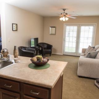 A cozy living room with a sofa, television, and a kitchen island.