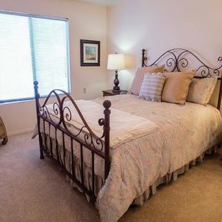 A cozy and elegantly decorated bedroom featuring a wrought iron bed, soft bedding, and warm lighting from a bedside lamp.