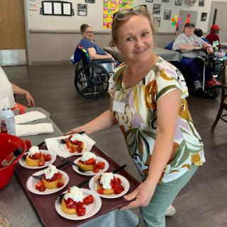A cheerful volunteer serves delicious strawberry shortcakes at a community gathering.