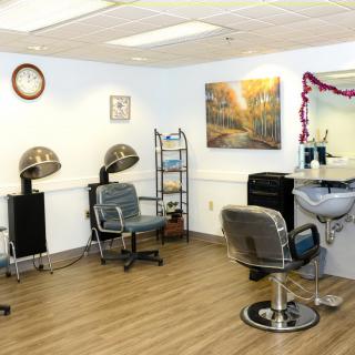 A cozy hair salon interior with chairs, hair dryers, and a mirror.