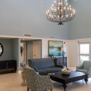 A modern living room featuring a large chandelier, comfortable seating, and elegant decor.