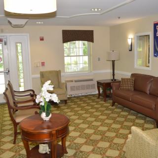 A cozy waiting area with comfortable seating, featuring a sofa, chairs, and a coffee table in a warmly decorated living room.