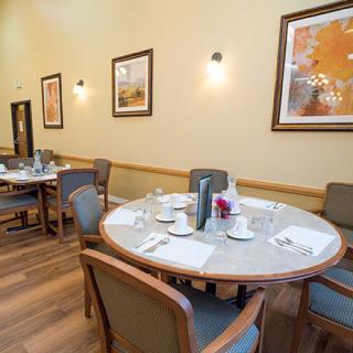 A well-arranged dining room with tables and chairs, decorated with artwork on the walls.