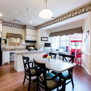 A bright and cozy kitchen with a dining area, featuring a table with chairs, ample lighting, and large windows.