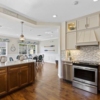 A modern kitchen with stainless steel appliances, hardwood floors, and an open concept dining area.
