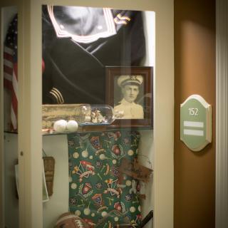 A display case featuring a military photograph, sports memorabilia, and an American flag.