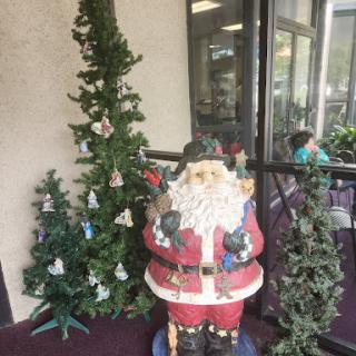 A festive display featuring a statue of Santa Claus surrounded by decorated Christmas trees.