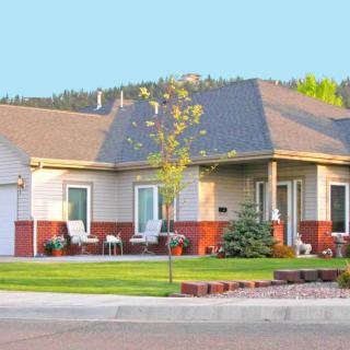 A suburban house with a well-maintained front yard and clear sky background.