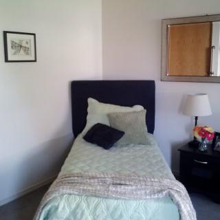 A neat bedroom with a single bed, nightstand, and lamp.