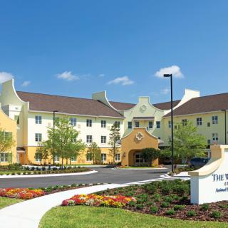 A hotel building surrounded by well-maintained gardens under a clear blue sky.