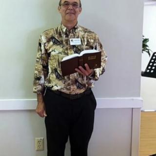 A person standing indoors holding an open book.