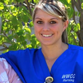 A smiling woman in a blue nursing uniform with 'WWCC' embroidered on it, standing outdoors.