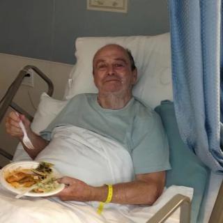 A patient in a hospital bed enjoying a meal.