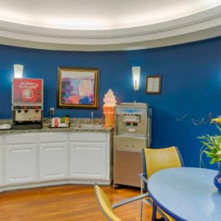 A cozy cafe corner featuring an ice cream machine and beverage dispenser against blue walls.