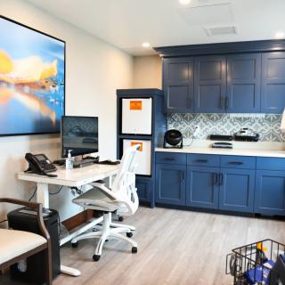 A modern home office featuring a sleek desk, computer setup, and stylish blue cabinetry.