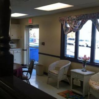 A cozy waiting room with wicker chairs, a table, and large windows letting in natural light.