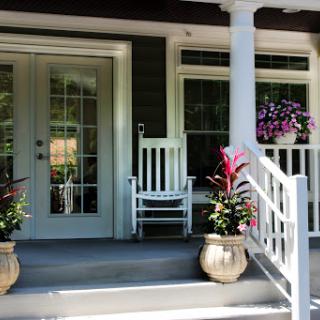 A welcoming front porch featuring a classic rocking chair and vibrant flower planters.