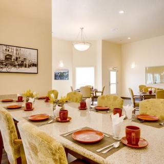 A beautifully set dining room table with red plates and mugs, ready for a meal.