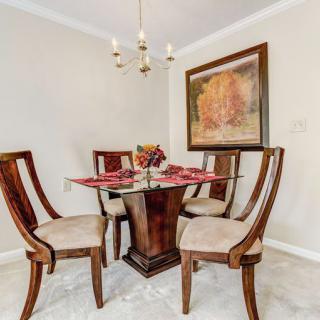 A cozy dining room with a wooden table and four chairs, enhanced by elegant artwork and a chandelier.