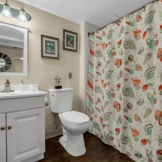 A cozy bathroom featuring a floral shower curtain and white fixtures.