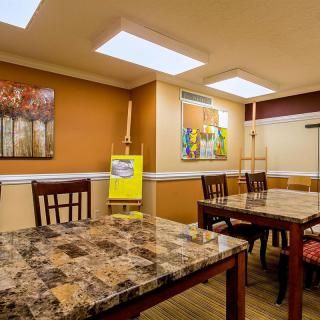 A cozy dining room with marble-topped tables and chairs, decorated with artwork and warm lighting.