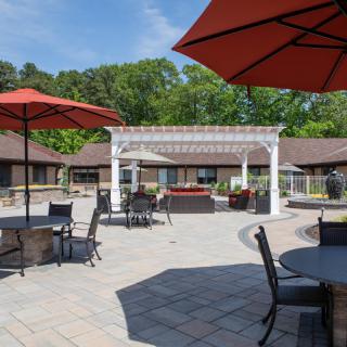 A sunny outdoor patio area with tables, chairs, and umbrellas.