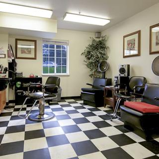A cozy barber shop with a checkered floor design, comfortable chairs, and stylish decor.