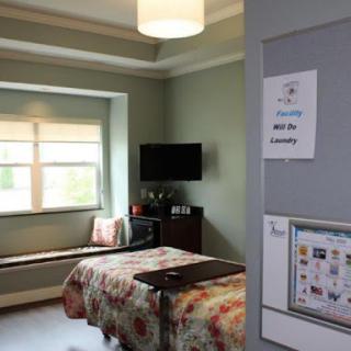 A cozy room featuring a bed, a television, and natural light from the window.