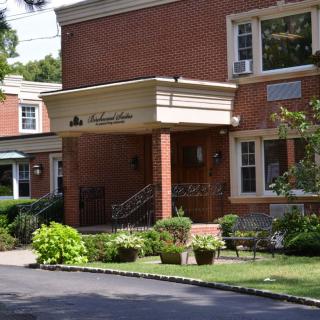 The entrance of a brick residential building surrounded by greenery.