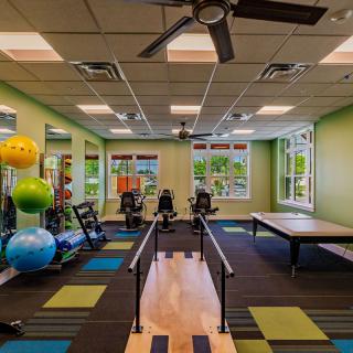 A bright and well-equipped fitness and therapy room with exercise equipment and colorful decor.