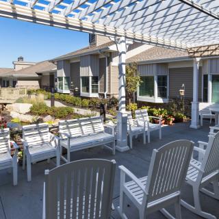 A sunny outdoor seating area with chairs and a shaded patio.