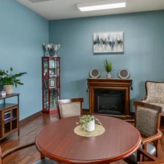 A cozy living room with a round table, chairs, fireplace, and decor elements on blue walls.