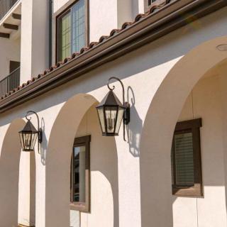 A Mediterranean-style building with arched doorways and decorative lanterns in the sunlight.