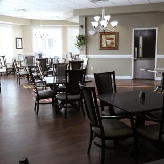 A spacious dining area with neatly arranged tables and chairs, well-lit by ceiling lights.