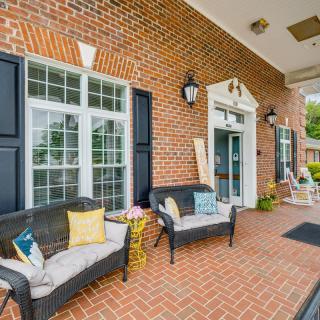 A cozy outdoor patio with seating and decorative cushions against a classic brick wall.