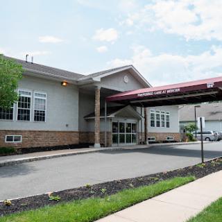 The entrance of a modern medical facility, featuring a covered walkway and landscaped surroundings.