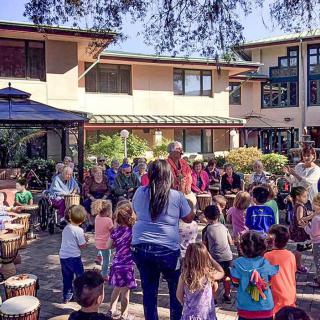 A diverse group of people, including children and adults, enjoy an outdoor community gathering.