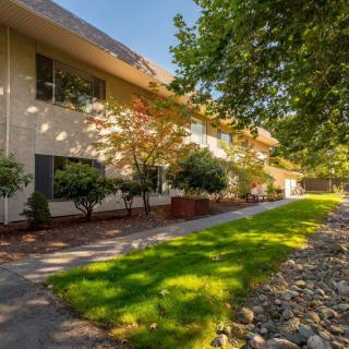 A well-maintained apartment building with a landscaped garden and a sunny pathway.