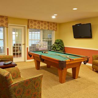 A cozy game room featuring a pool table, comfortable seating, and a wall-mounted TV.