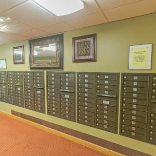 A hallway with rows of wall-mounted mailboxes and framed art on the walls.