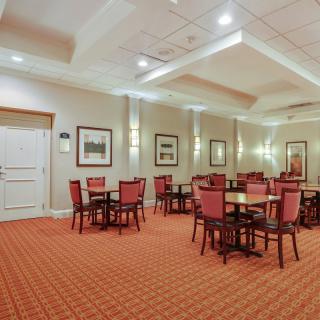 A well-lit conference room with red chairs and tables arranged for meetings.