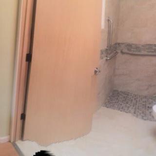 A bathroom flooded with water spilling under the door into another room.
