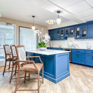 A modern kitchen with vibrant blue cabinets and a central island, featuring bar stools and pendant lighting.