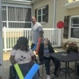 A group of people enjoying a sunny day on the patio with pool noodles.