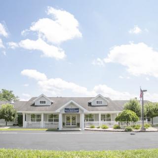 A sunny day with a building surrounded by trees and a parking lot.