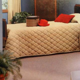 A cozy bedroom featuring a quilted bedspread with accent pillows, a red hat, and a decorative basket on the bed.